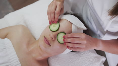 caucasian woman lying back while beautician gives her a facial