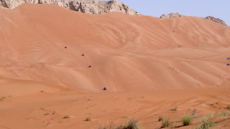 four-wheel vehicles driving on a hot arabian desert at fossil rock in sharjah near dubai, uae