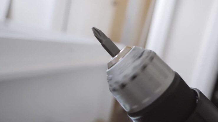Close up of a drill slowly spinning in the air with a white background