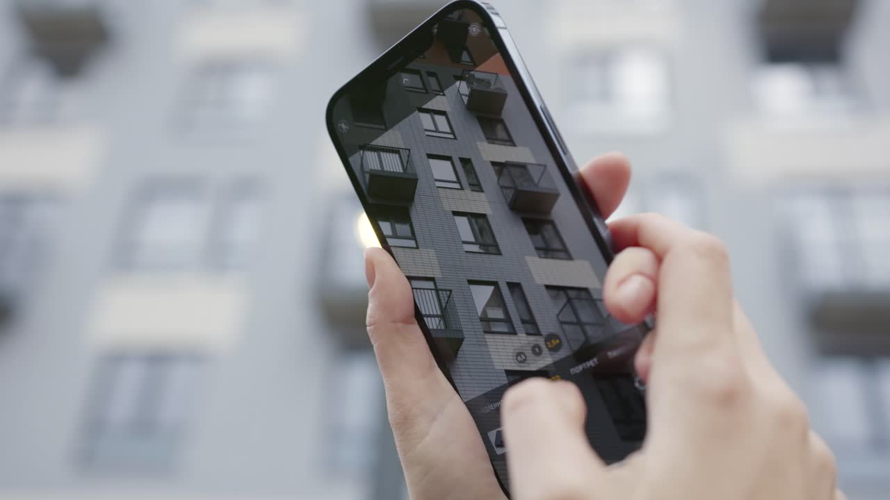 persona tomando una foto de un edificio moderno con un teléfono inteligente