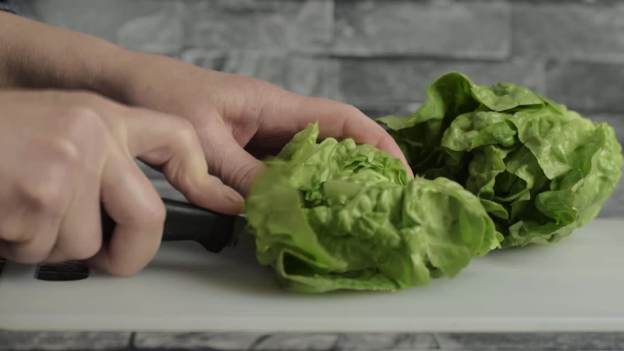 Hand cutting fresh gem lettuce in kitchen medium shot