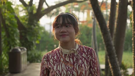 portrait of a smiling young asian woman in a park
