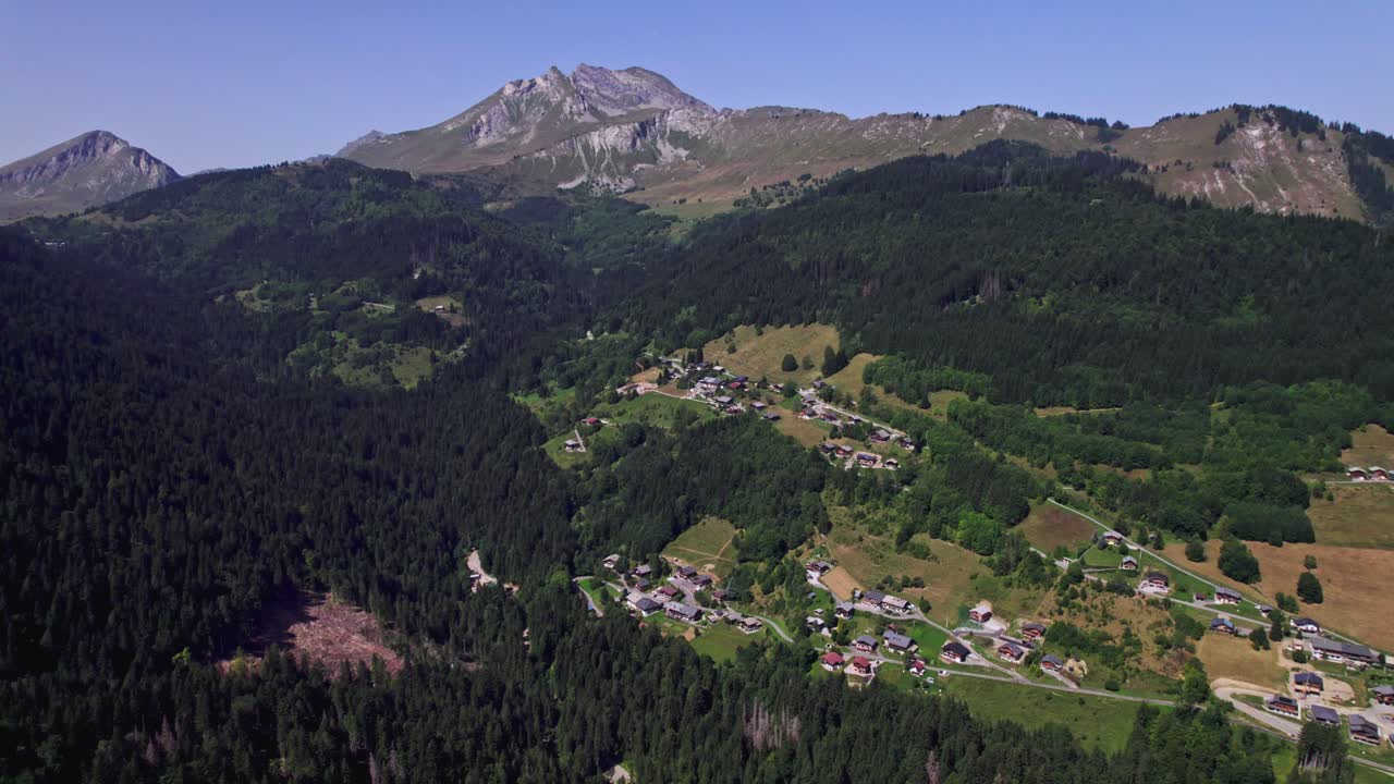 Aerial view of a village nestled in a mountain valley with dense forests