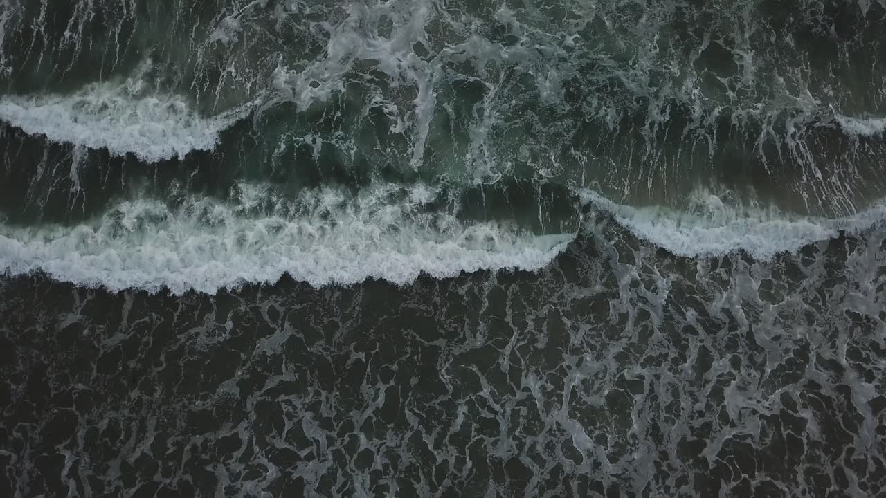 Static cenit view from a drone over the coast showing the waves on the beach on a cloudy day