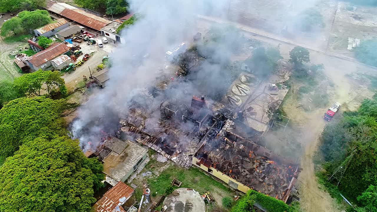 vista aérea alejándose de un incendio en un edificio, una estructura fumando en el campo, en méxico, américa central - órbita, disparo de drones