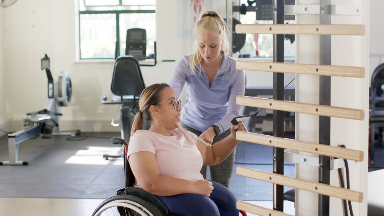 Exercising with therapist, woman with paraplegia in wheelchair using equipment in rehabilitation