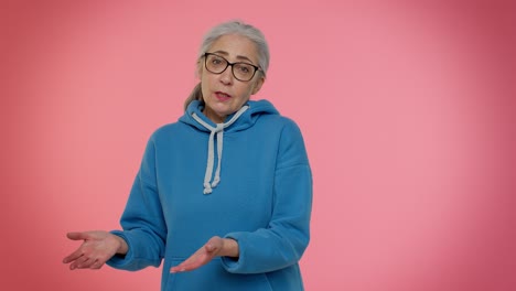 una mujer con cabello gris y gafas está hablando con la cámara.