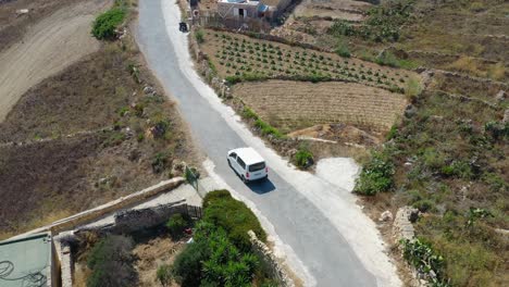 aerial drone footage overhead car on road towards wied il-għasri in malta