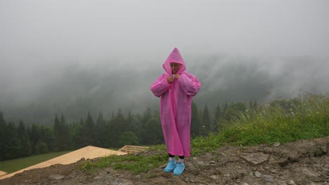 mujer con impermeable rosa en las montañas de niebla