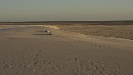 offroad vehicles explore windy brazil dunes with sand gusts in sunset