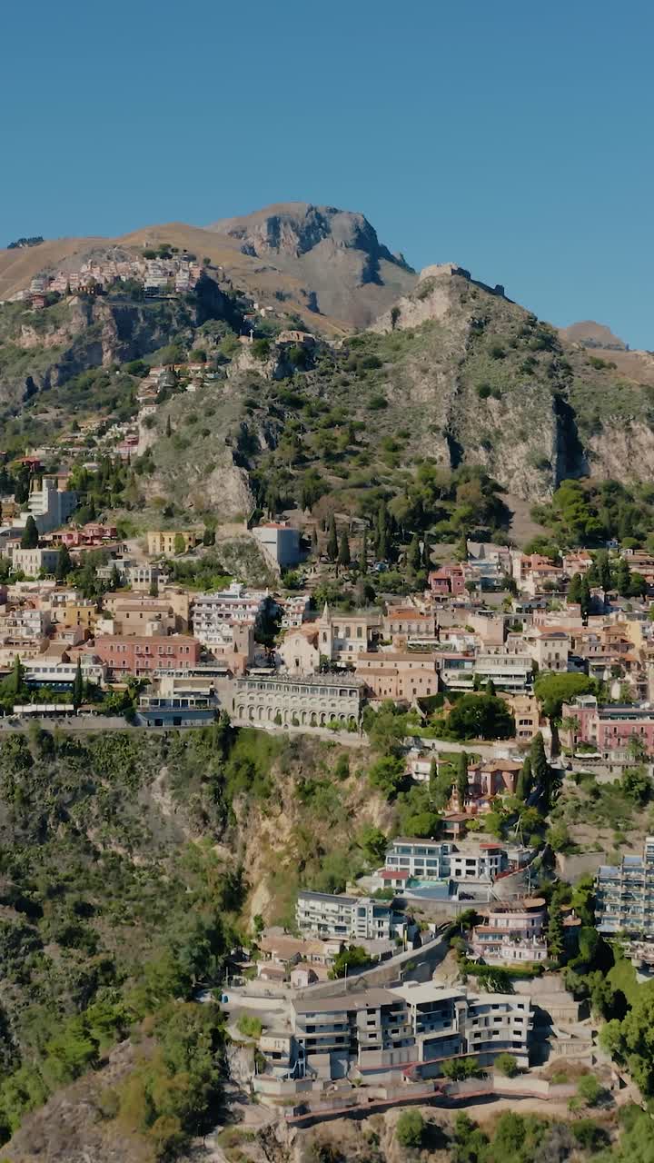 drone vertical disparado volando hacia la encantadora ciudad histórica italiana al pie de las montañas. increíbles vistas panorámicas de taormina en sicilia.