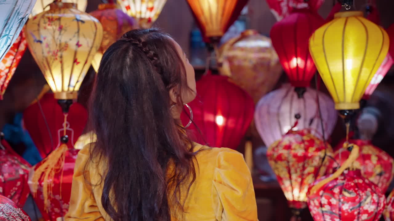 fotografía de una joven vietnamita navegando por una tienda de linternas coloridas en hoi an, vietnam