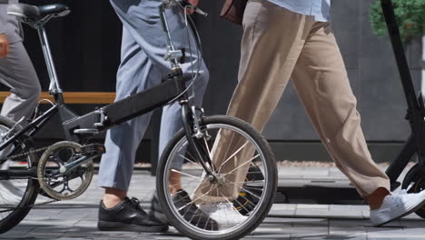 workers legs walking downtown with electric scooter bicycle in hands close up.