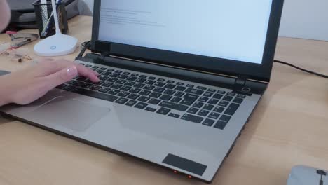 Modern technology in use: hands typing on a laptop displaying Hebrew script.