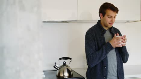 Man-having-a-cup-of-coffee-in-kitchen