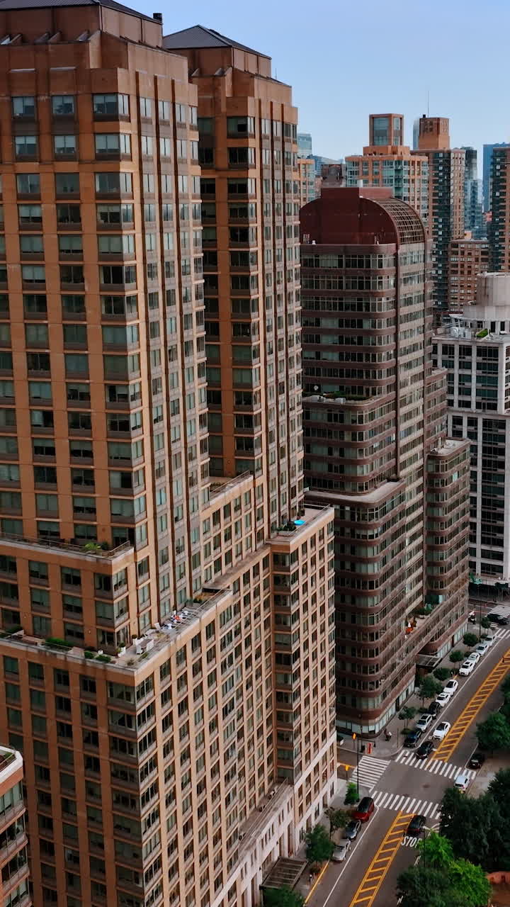 Closer look on the beautiful New York buildings standing near the waters of Hudson. Cozy green areas and lively highway near the buildings. Top view. Vertical video