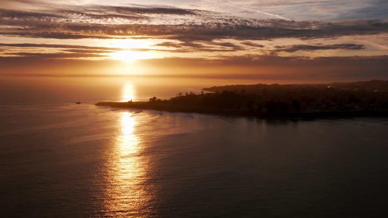 tomada panorámica de una antena de avión no tripulado sobre una península en santa cruz al atardecer con surfistas