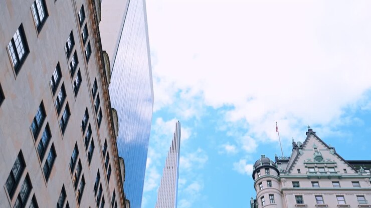 Numerose auto sono ferme sulla strada in attesa del semaforo. Vista dal basso verso gli splendidi edifici di New York con una bandiera americana sulla facciata.