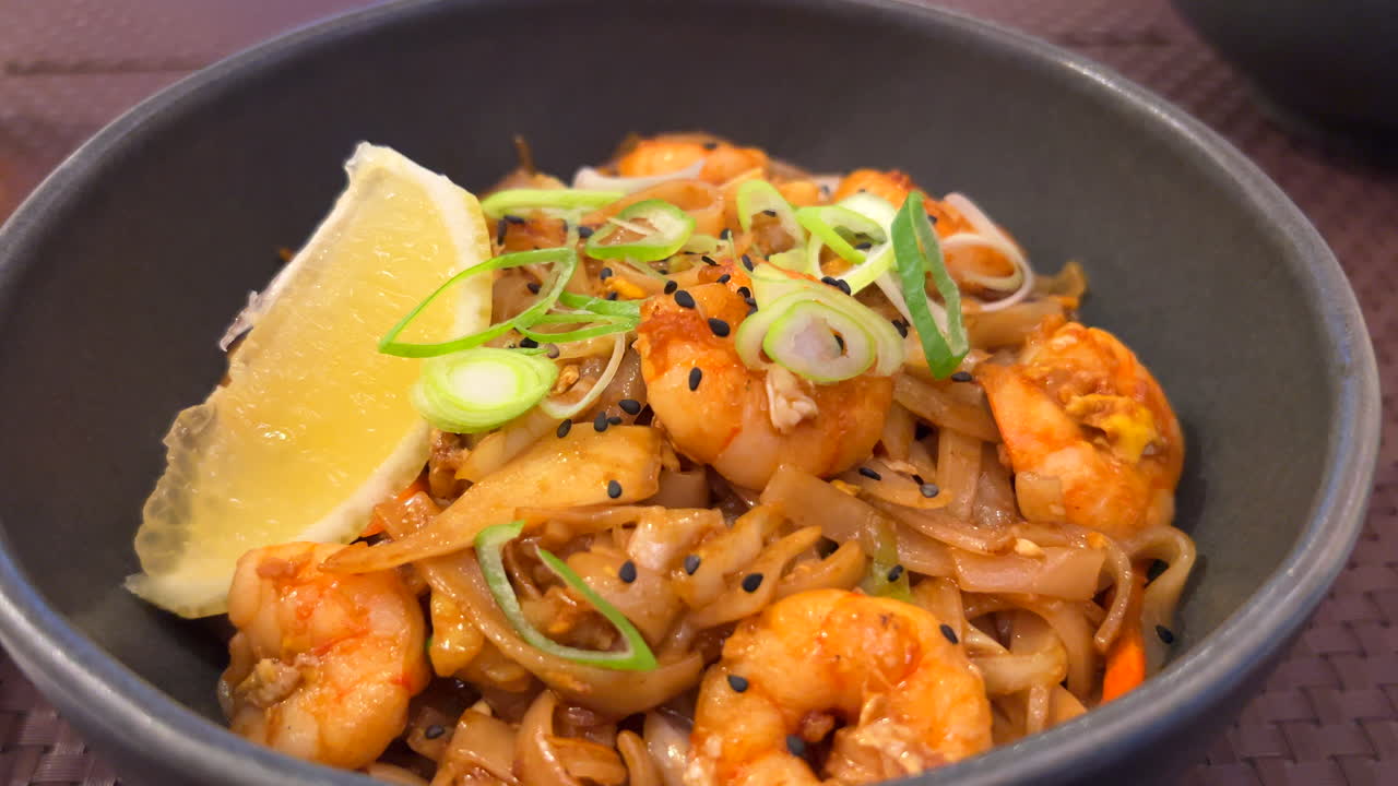 fideos tradicionales pad thai wok con camarones, cebolla de primavera y una rebanada de limón, restaurante tailandés, sabrosa comida asiática, tiro de 4k