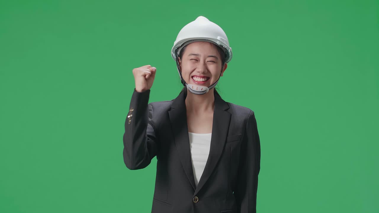 Happy Asian Female Engineer With Safety Helmet Celebrating While Standing On Green Screen In The Studio