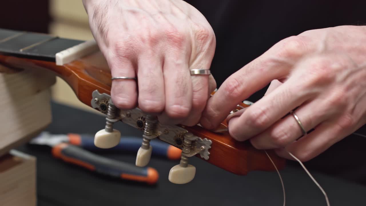 Caucasian luthier cleans guitar pegbox takes off strings cut with tool