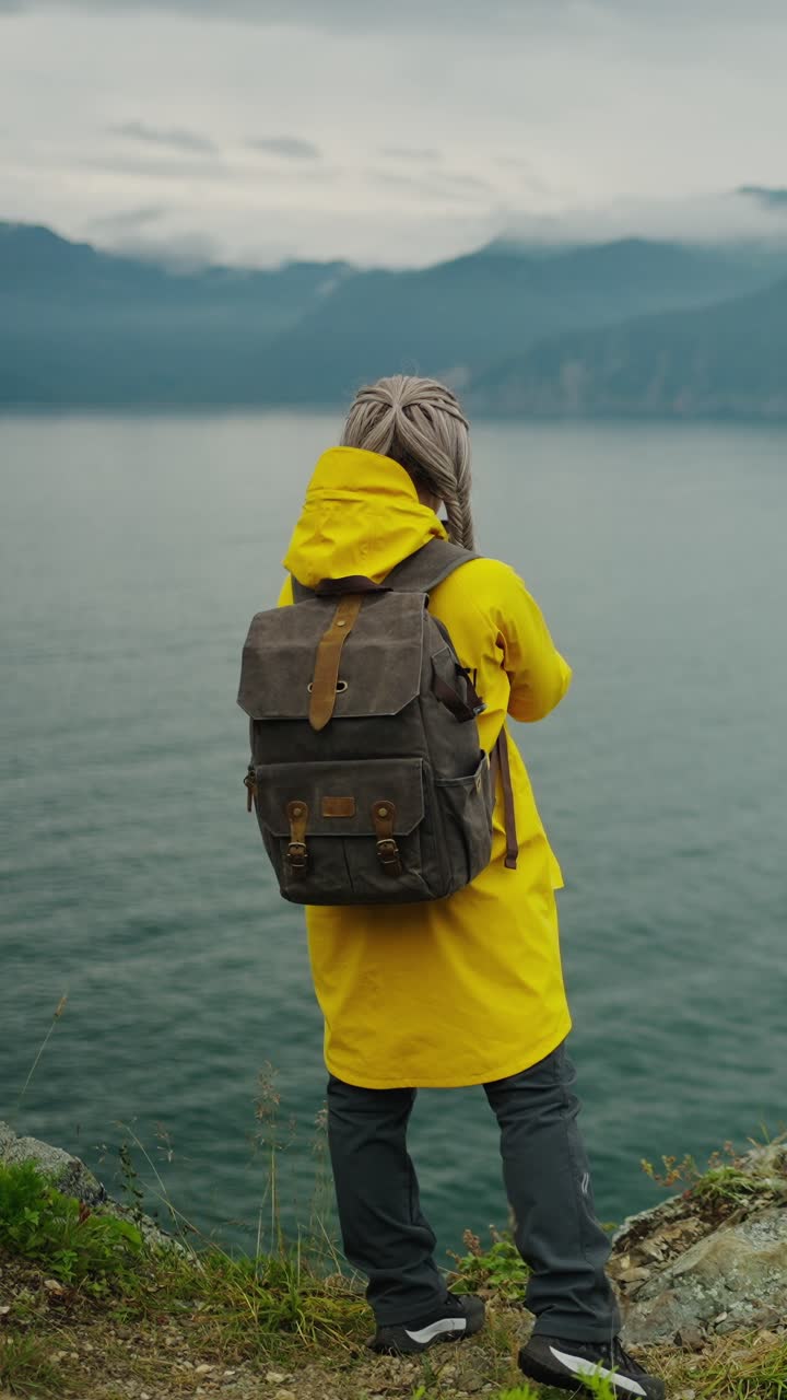 Donna con zaino che contempla una vista panoramica sul lago