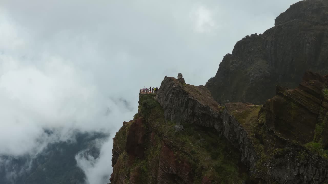 Hikers at viewpoint on Pico do Arieiro, Madeira, mountains shrouded in clouds and fog. Aerial drone