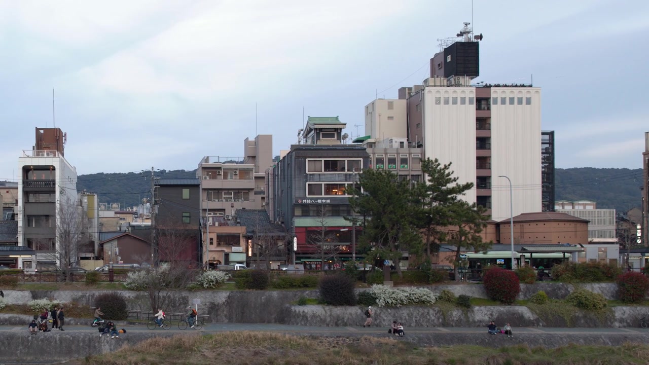 Plano geral de pessoas caminhando e andando de bicicleta ao longo do Rio Kamo em Quioto, Japão