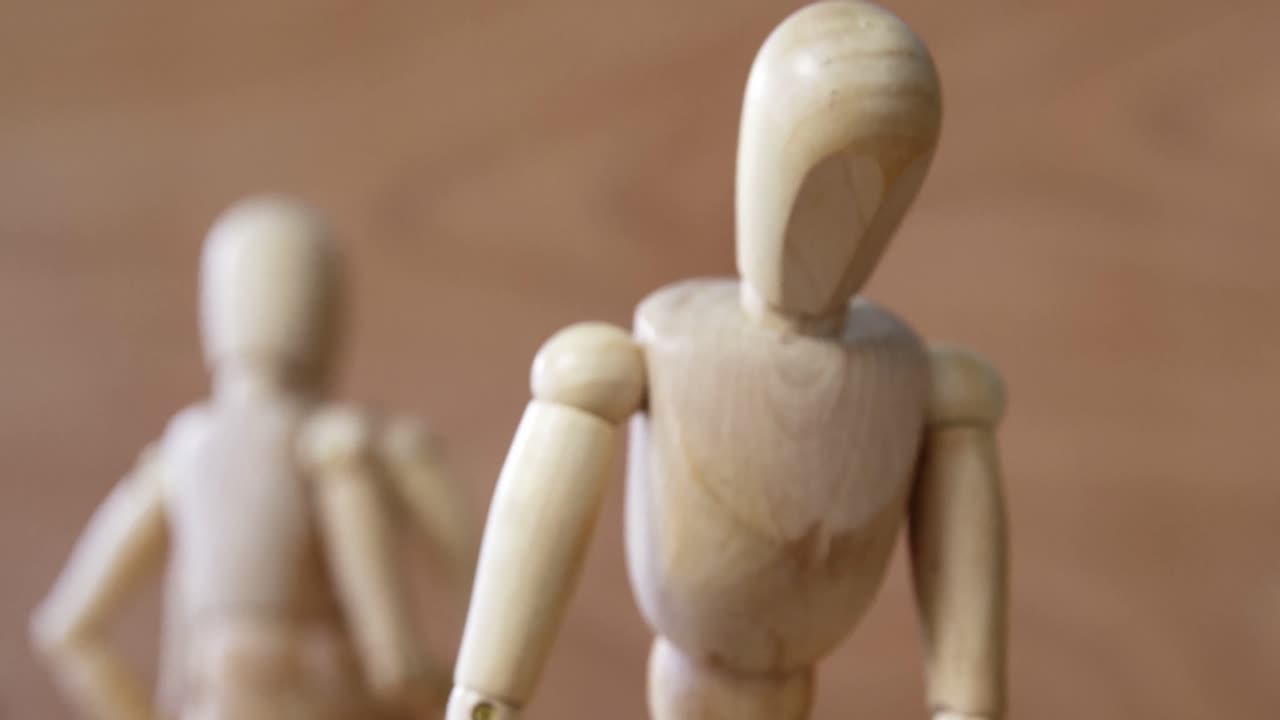 estatuilla de madera con un ramo de rosas celosa con otra pareja sobre un fondo de madera