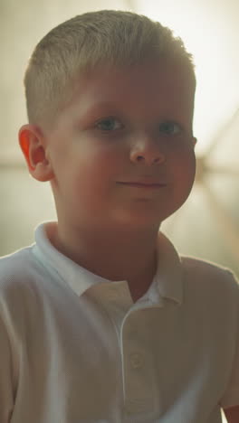 portrait of preschooler boy near illuminated glamping tent. cheerful kid smiles enjoying tourist trip natural places closeup. little hiker rests in evening on blurred background