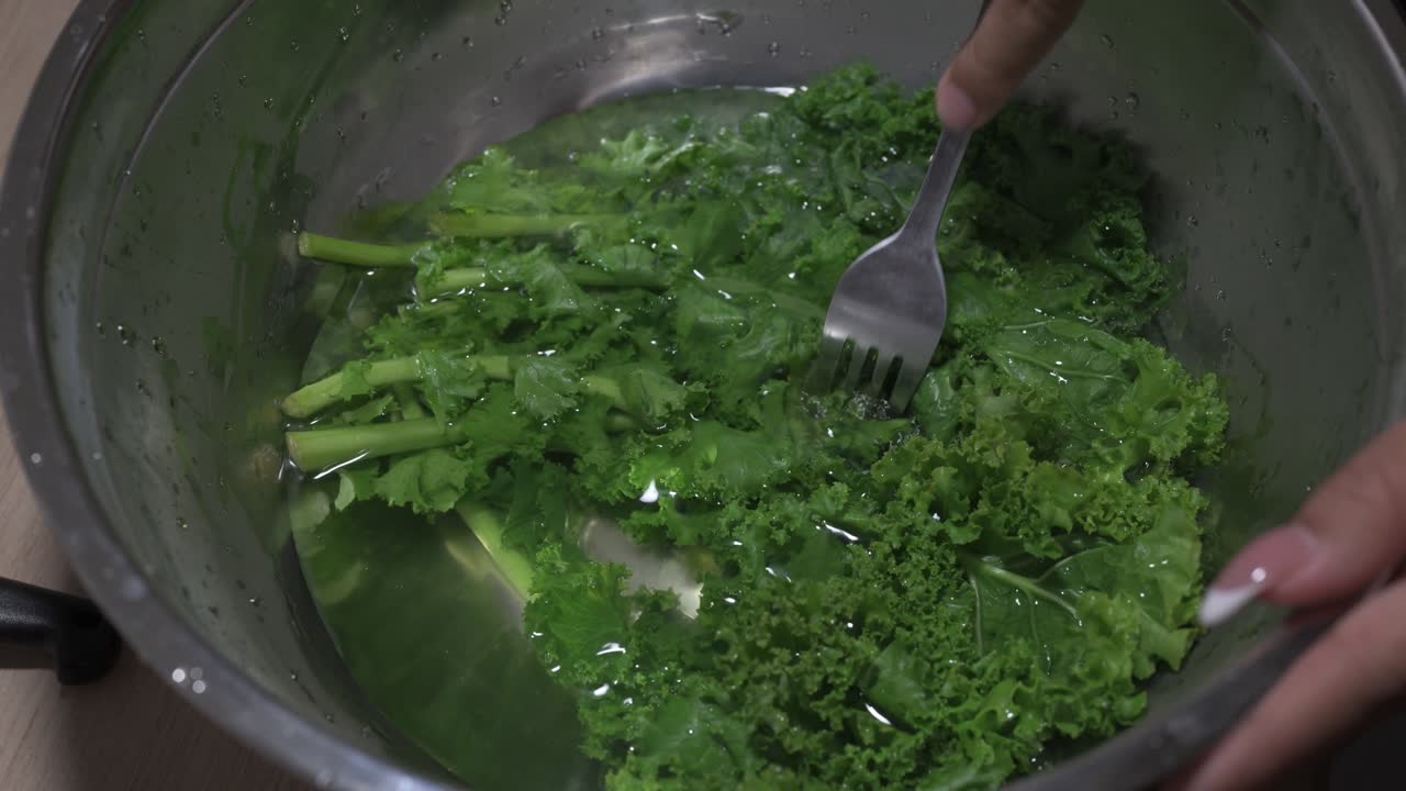 Kale being cleaned and prepared at home kitchen close-up horizontal view