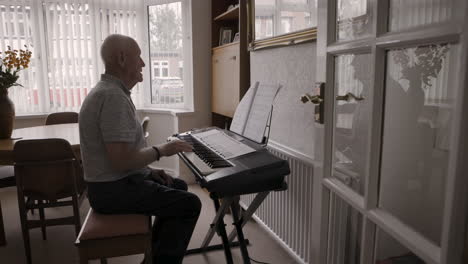 senior man playing keyboard at home