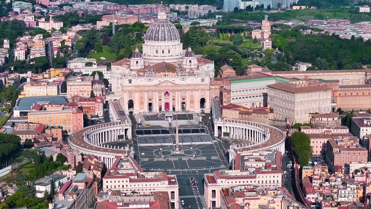Vista aerea della Basilica di San Pietro e Piazza San Pietro nella Città del Vaticano, che mostra l'iconica cupola, i colonnati del Bernini e il paesaggio urbano circostante di Roma alla luce del giorno.