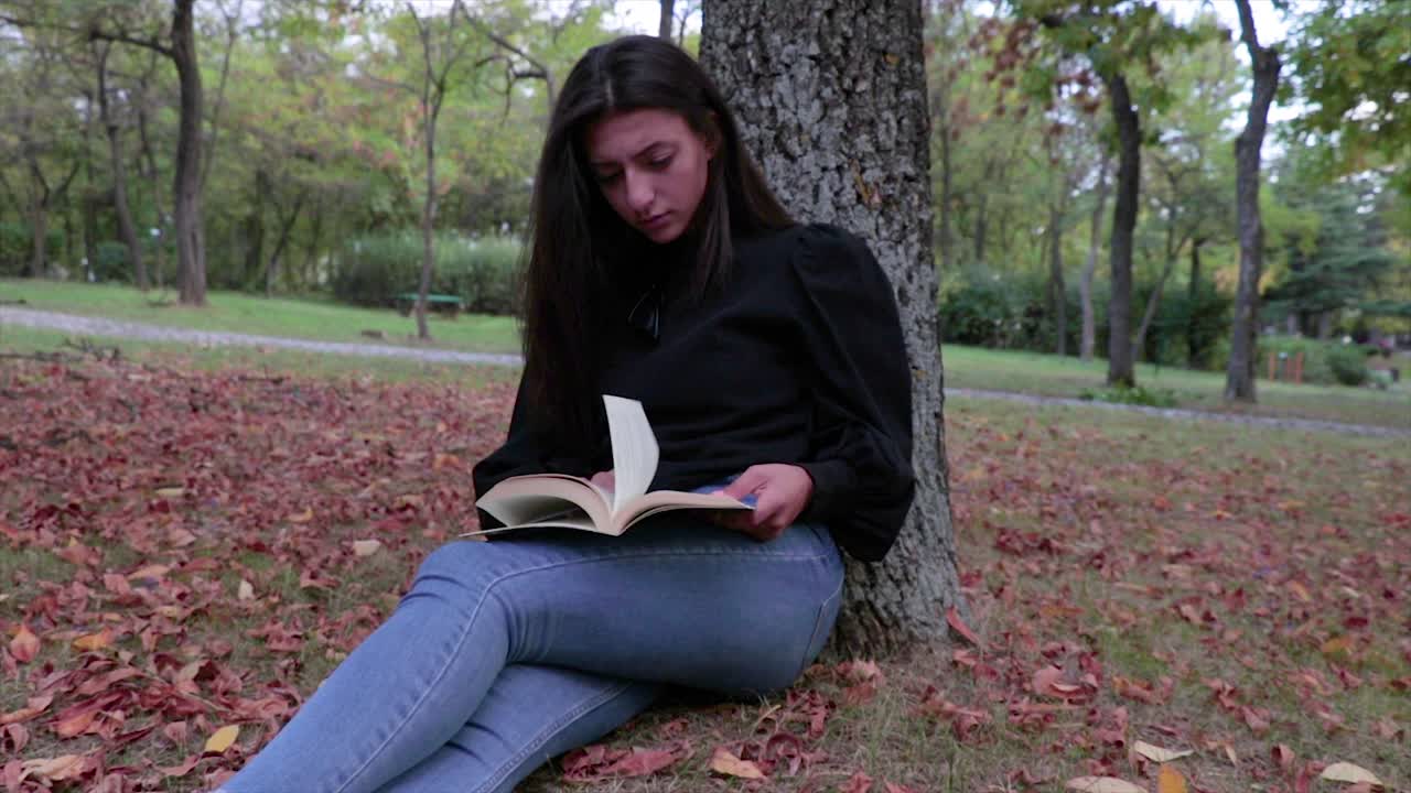 niña leyendo un libro en un parque en otoño