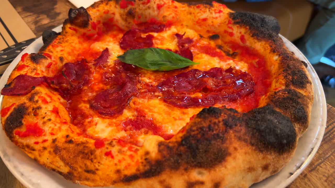 Traditional Italian spicy pepperoni pizza with a fresh basil leaf, perfect crust, real authentic Neapolitan pizza, tasty food, 4K shot