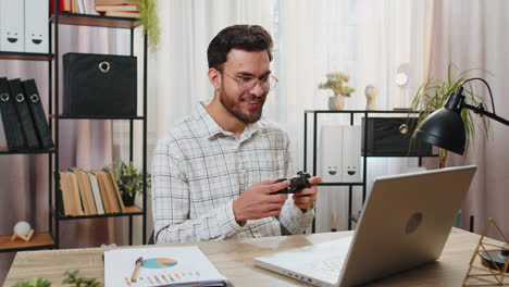 un hombre de negocios indio celebrando la victoria en un videojuego en una computadora portátil apretando los puños pasando el tiempo libre