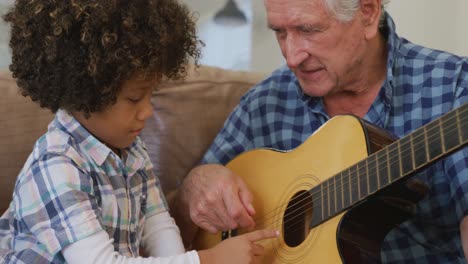 video de un nieto biracial y un abuelo caucásico tocando la guitarra juntos