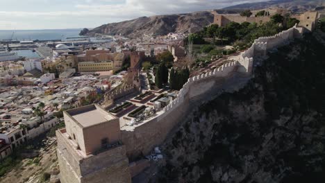 Aerial-ascending-revealing-Scenic-Alcabaza-of-Almería,-by-mediterranean-Sea