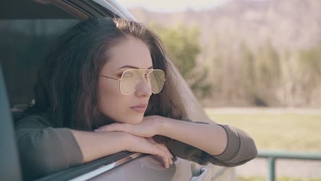 Una-Mujer-Con-El-Pelo-Suelto-Y-Gafas-Elegantes-Se-Asoma-Fuera-Del-Coche