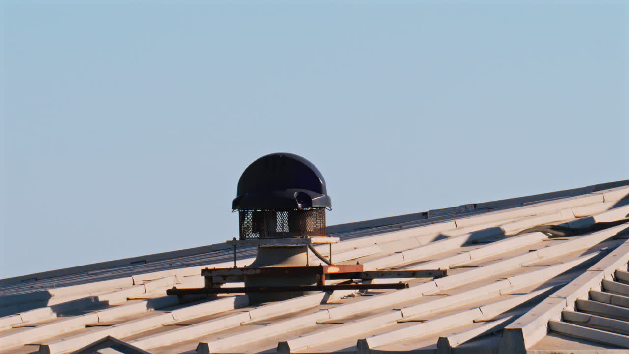 Close-up of a ventilation system mounted on a metal roof with the blue sky on the background