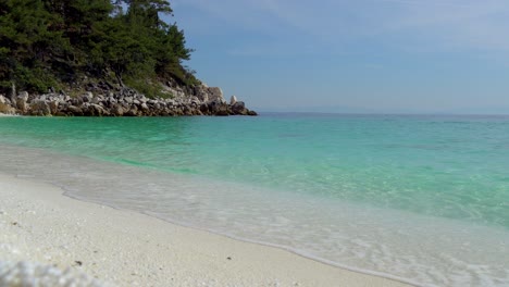 Olas-Salpicando-En-Una-Playa-De-Guijarros-Blancos-Con-Un-Cielo-Azul-Claro-En-El-Fondo,-Playa-De-Mármol,-Isla-De-Thassos,-Grecia