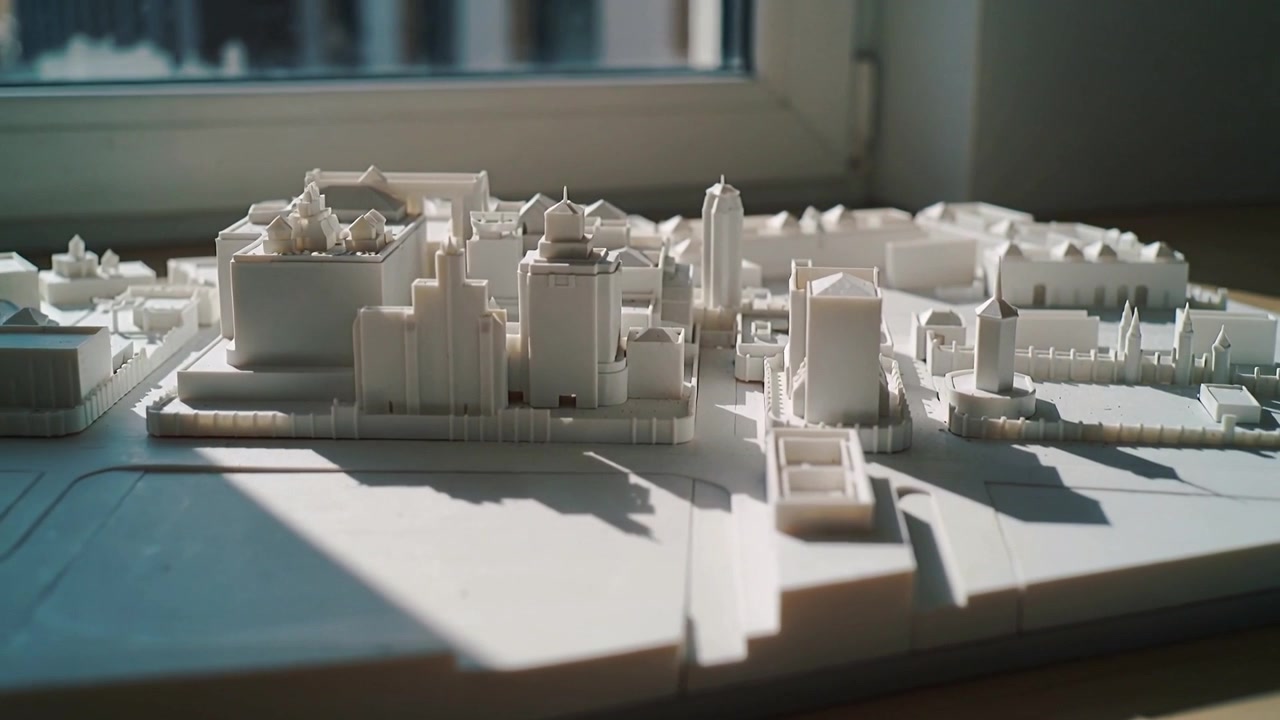 Panning camera low, rising right, showing white architectural model on table by window for layout