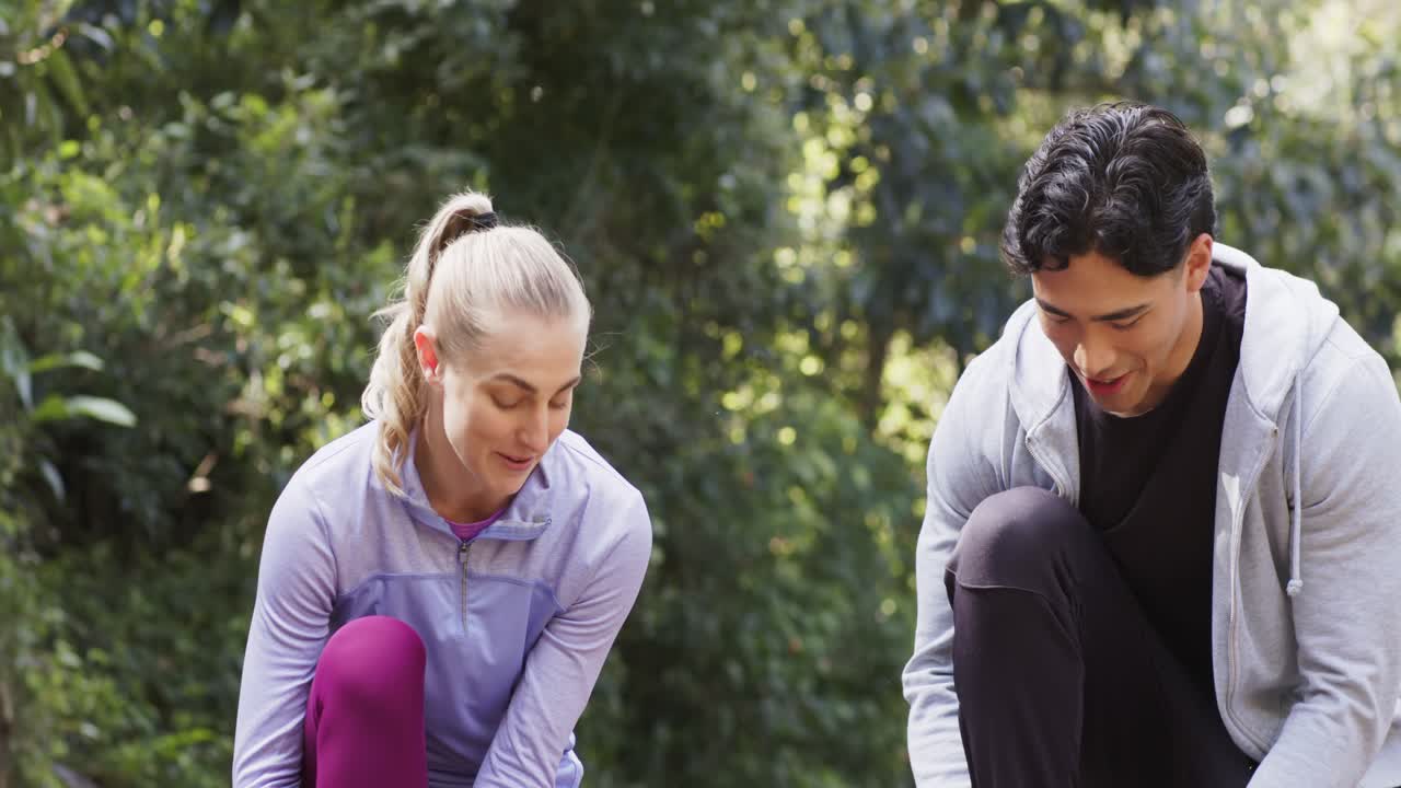 Preparativi per la corsa: un gruppo di amici diversi si allaccia le scarpe da corsa prima di fare jogging sul sentiero del parco
