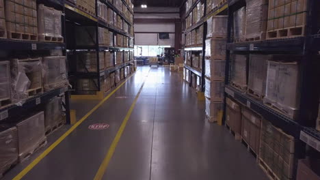 forward aerial shot of boxes on tall shelves in industrial warehouse