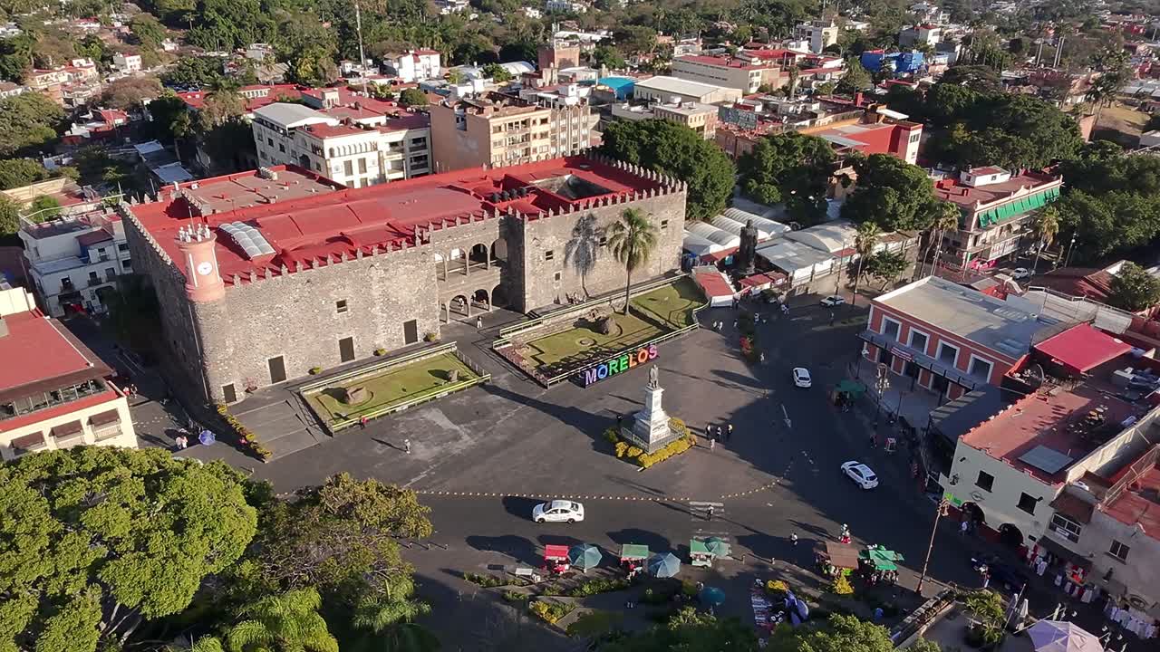 Aerial shot of Palacio de Cortés in Cuernavaca, Mexico, with the Carlos Pachecho statue, plaza, and surrounding streets