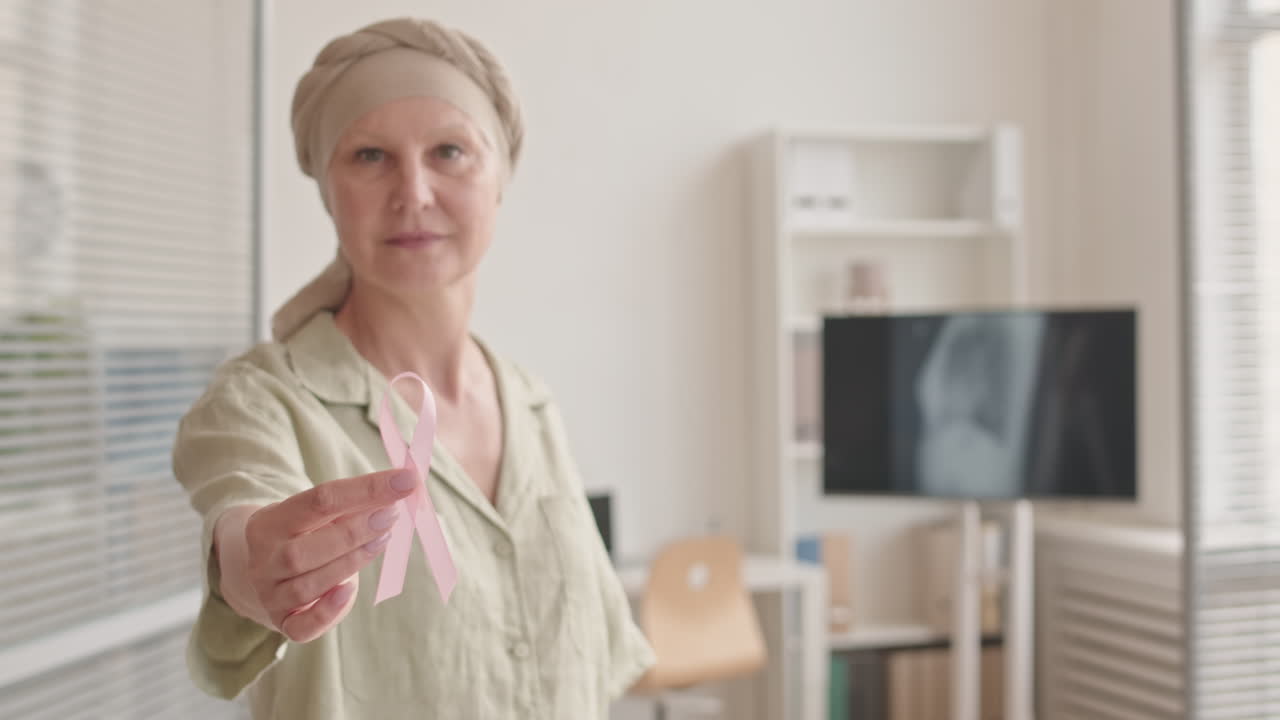 Mulher com câncer segurando fita rosa