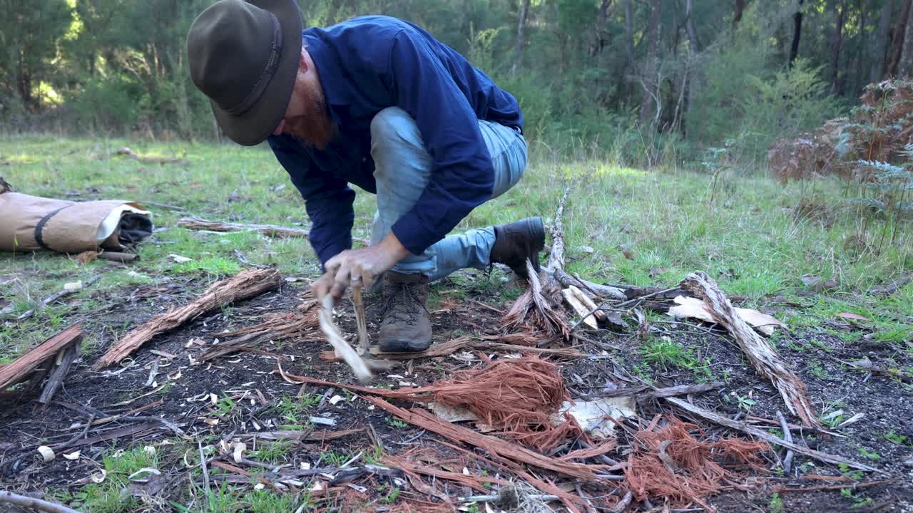 A traditional swagman bushman in Australia making fire with a bow drill