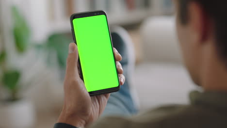 young-man-using-smartphone-watching-green-screen-enjoying-entertainment-on-mobile-phone-chroma-key-display-horizontal-orientation-4k-footage