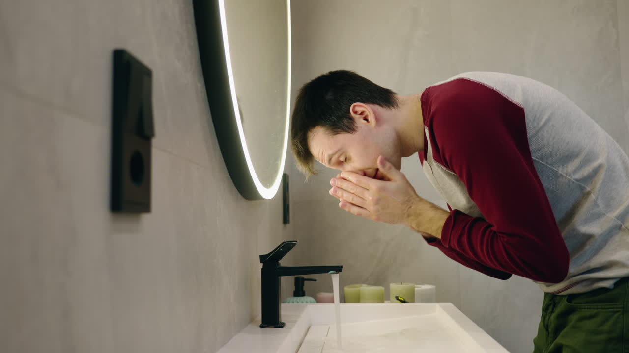 человек моет лицо в ванной.