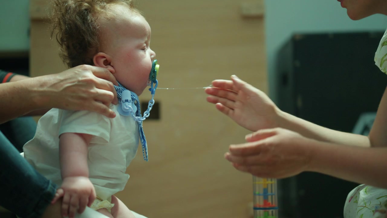 Mother helping a distressed baby by offering a pacifier, providing comfort and care during a challenging moment